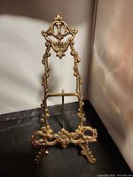 Front view of brass easel showing ornate floral design and overall form