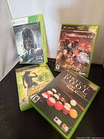 Front view of four game cases: Dishonored, MechAssault, Karaoke Revolution, Virtual Pool