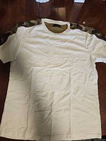 Full front view of white T-shirt displaying camouflage shoulder panels