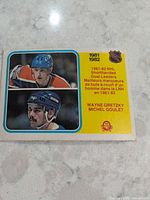 Front of card featuring Gretzky (upper image) and Goulet (lower image) with NHL shield and season text