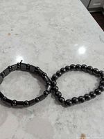 Two hematite bead bracelets side by side on countertop