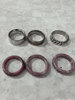 six rings laid out, three metal bands and three stone rings