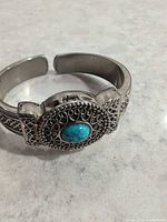 Front view of cuff watch showing filigree cover with turquoise cabochon