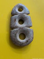 Front view of carved stone pendant showing triple holes and overall shape