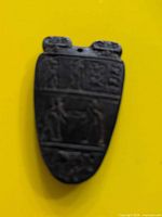 Front view showing carved figures and characters on pendant