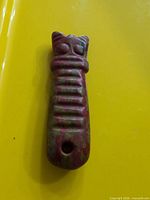 front view of carved stone pendant showing cat motif and hanging hole