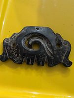 Front view of ornate metal plate showing scroll design and mounting holes