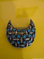 Front view of brooch showing lattice design and turquoise cabochons