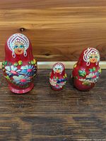 Front view of three red floral nesting dolls