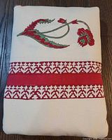 Tablecloth folded showing corner floral motif and red geometric border