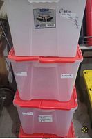 Three stacked translucent totes with red lids showing labels and writing
