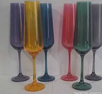 Six assorted coloured champagne flutes standing