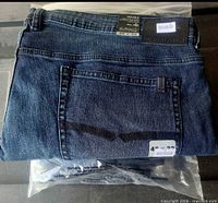 Folded Buffalo Travis-X jeans showing rear pocket, leather patch, size tag, plastic packaging underneath