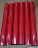Six red mailing tubes aligned side-by-side