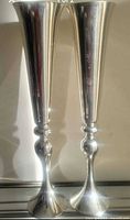 Front view of both tall polished metal trumpet vases
