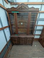 Full view of the wooden glass display cabinet showing top glass section and lower carved doors