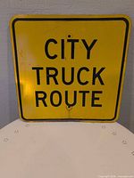 Front of yellow CITY TRUCK ROUTE steel sign