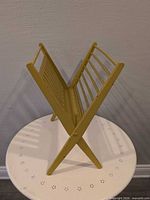 Overall view of mustard yellow wooden folding magazine stand