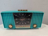 Front view showing turquoise cabinet, clock face, knobs