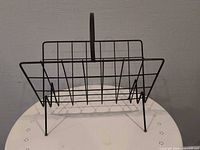 Front view of black steel wire magazine rack showing overall structure