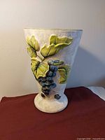 Front view of ceramic vase showing grape and leaf relief