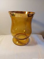 Full side view of amber pedestal vase showing shape and color