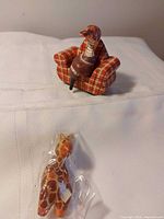 Goose figurine seated on plaid armchair with giraffe figurine in plastic
