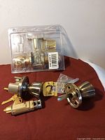 Both locksets overview on red surface; packaged passage set and loose keyed entry set with keys visible