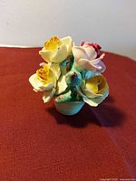 Front view of porcelain flower arrangement showing multicolor roses and leaves