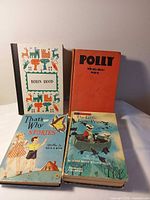 Group shot of all four hardcover children’s books standing and laying on surface