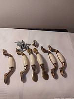 All six drawer pulls, knob, and screws displayed on fabric surface