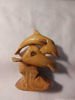 Front view showing three carved dolphins on base