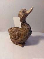 Front view of brown textured duck figurine with tag attached