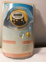 Front of sealed package showing round yellow/black player and 1GB marking