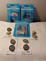 All items overview: four plastic button blister packs behind, four Elan metal button cards front