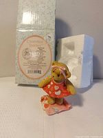 Front view of figurine beside original box and styrofoam insert