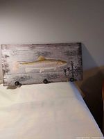 Front view of wooden rack showing trout graphic and all three hooks