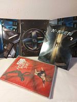 Both DVD sets: X-Men open case showing discs and American Horror Story Season 1 sealed