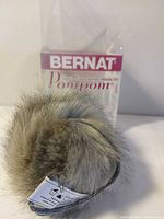Front view of Bernat faux fur pompom in package