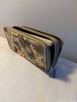 Wallet standing showing exterior floral print and zipper edges
