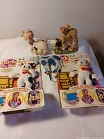 Overview of all cow themed items: two packaged plush toys, ceramic cow, resin figurine, blue ornament