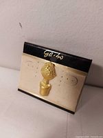Front view of gold-tone trophy lapel pin on Sabo card