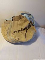 Front view of beige canvas Patons tote with logo and blue trim
