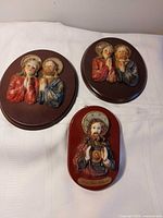 Three resin wall plaques on white cloth showing overall lot