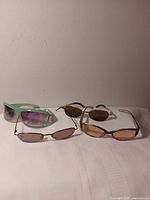 All four pairs laid out: green plastic, bronze metal with rose lenses, brown plastic with grey lenses, gold metal with brown lenses