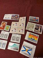 Full assortment of Canadian mint stamps laid out on red surface