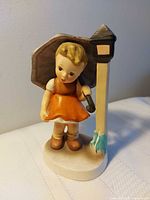 Front view of porcelain girl figurine with umbrella and lamppost