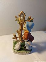 Front view of figurine showing girl, geese, tree and birdhouse