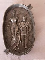 Front view showing raised relief couple, cigarette rests visible