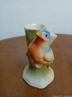 Front view of glazed ceramic bud vase with perched bird